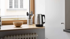A kitchen with a wooden bowl, a kettle, and utensils on a window sill. - Grand Apartment close to the Isar and Citycenter (München)