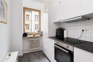 Eine moderne Küche mit Fenster, einer Kaffeemaschine und einem Backofen.