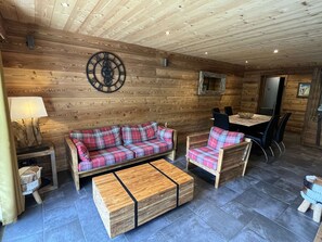 Un intérieur en bois comprenant un canapé, des fauteuils, une table et une horloge décorative.