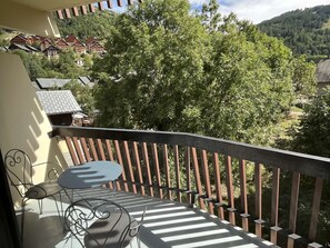 Een balkon met een tafel en stoelen, met uitzicht op een dorp en bomen.