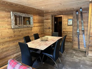 Ein Holzinnenraum mit einem Esstisch, Stühlen, einem Spiegel und Ski.