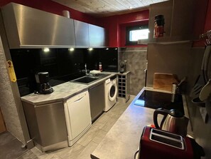 A compact kitchen with stainless steel appliances, a washing machine, and a toaster. - Spacious apartment with balcony - 7 guests (Valloire)