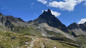 Een bergachtig landschap met een markante piek, heldere lucht en een pad dat naar de top leidt.