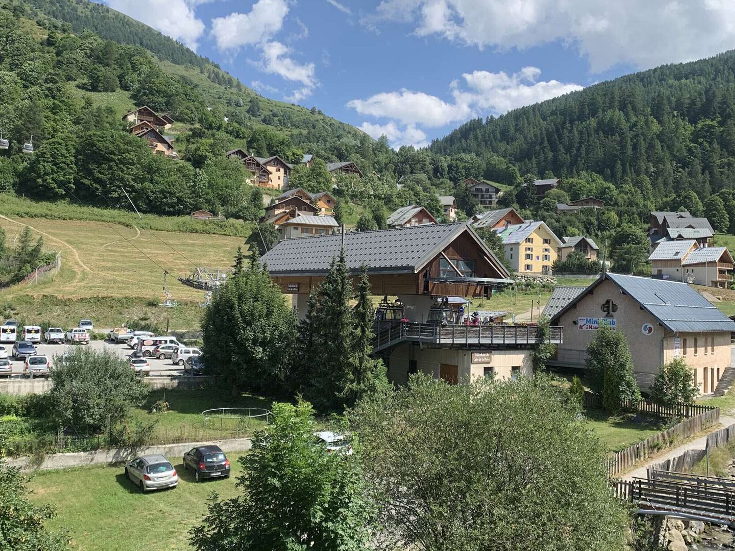 Ein Bergdorf mit Chalets, einem Parkplatz und einer kleinen Brücke.