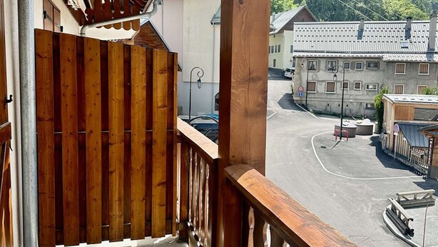 A balcony with a wooden railing overlooking a parking area and buildings. - Studio in the center - pets welcome - 4 guests (Valloire)