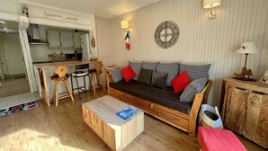 Een gezellige woonkamer met een bank, salontafel en een eethoek met stoelen.