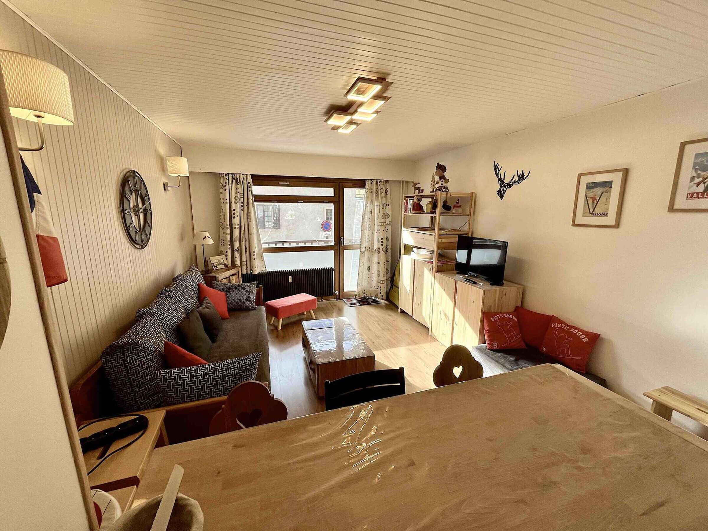 Een gemeubileerde woonkamer met een bank, een televisie, een houten kast en een eettafel.