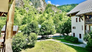 Un bâtiment à la façade blanche, entouré d’une pelouse bien entretenue et d’arbres, avec une montagne en arrière-plan.