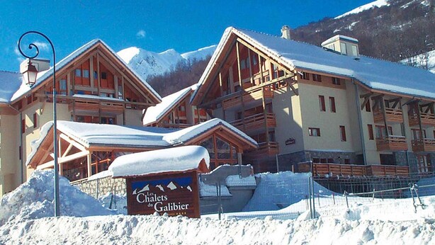 Un hôtel de style chalet, doté de balcons en bois et d’une enseigne indiquant « Les Chalets du Galibier ».