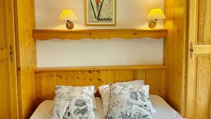 Une pièce en bois avec un lit, deux lampes et un tableau encadré au mur.
