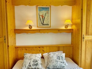 Een houten kamer met een bed, twee lampen en een ingelijste foto aan de muur.