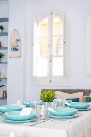A dining table set with teal plates, glasses, and cutlery, with a potted plant in the center. - My Sevillian Retreat (Seville)