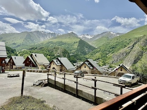 A mountain village with traditional chalet-style buildings, a parking area, and a view of the surrounding mountains. - Cozy apartment with elevator - 4 guests (Valloire)