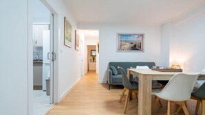Un comedor moderno con una mesa y sillas de madera, un sofá gris y un cuadro en la pared.
