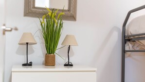 Un aparador blanco con dos lámparas y una planta.