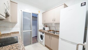 Una cocina compacta equipada con lavadora, microondas y refrigerador.