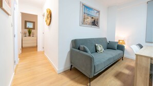 Una sala de estar moderna con un sofá gris, una mesa de comedor de madera y un cuadro de una playa.