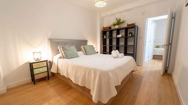 Un dormitorio con cama, mesita de noche y estantería.