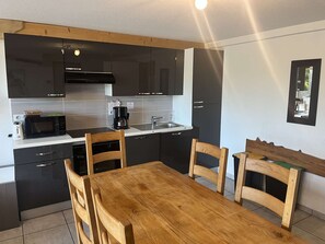 A compact kitchen with modern appliances, a dining table, and chairs. - Comfortable apartment with parking - 6 guests (Valloire)
