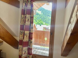Eine Holztreppe führt zu einem Balkon mit Blick auf einen bewaldeten Hang.