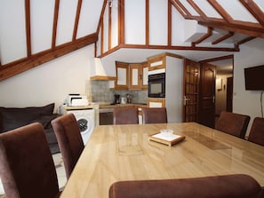 Eine moderne Küche mit Holzbalken, einem Essbereich mit Holztisch und -stühlen sowie einer Waschmaschine.