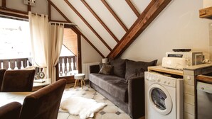 Ein gemütliches Dachzimmer mit einer Couch, einer Waschmaschine und einem Essbereich.