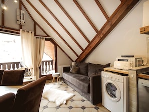 Ein gemütliches Dachzimmer mit einer Couch, einer Waschmaschine und einem Essbereich.