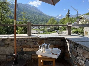 A stone wall with a wooden table and a tray of white cups and a teapot. - Cozy chalet, parking - 12 guests (Valloire)