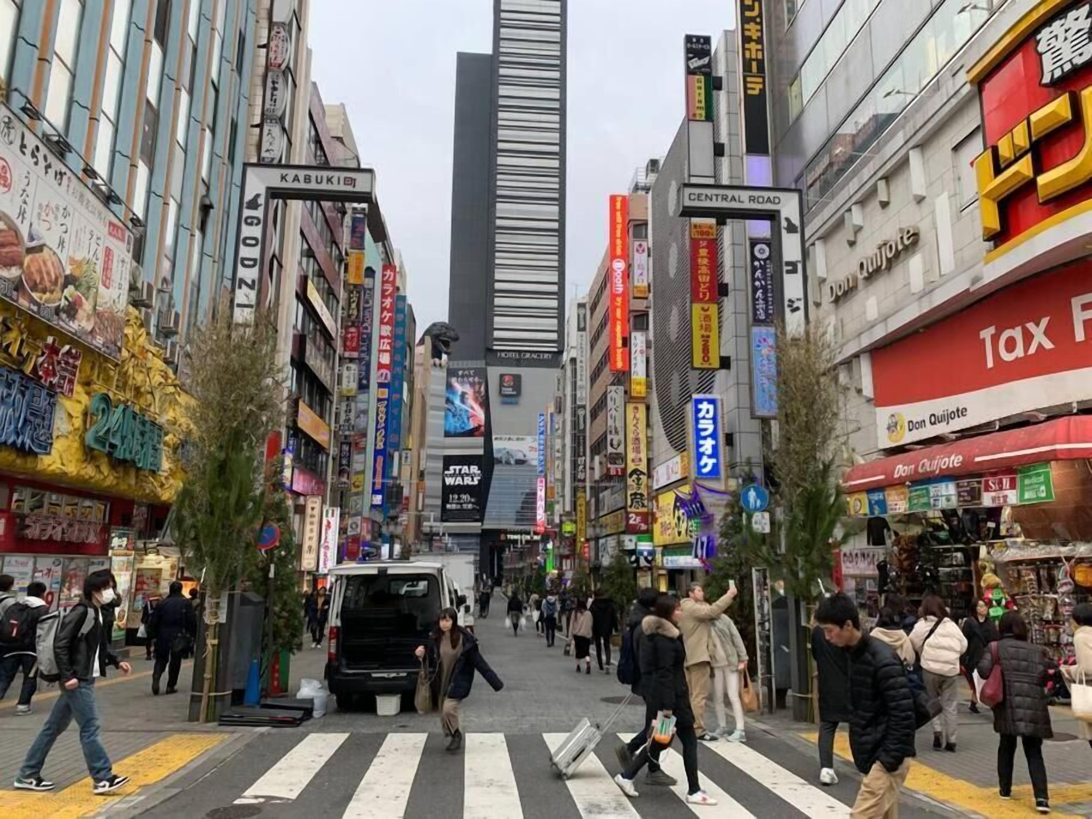 Una calle urbana concurrida con diversas tiendas y letreros, incluyendo un llamativo letrero que dice 'Central Road' y un letrero de 'Impuestos'.