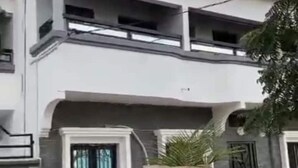 Un edificio de varios pisos con fachada blanca, ventanas grandes y un balcón en el piso superior.