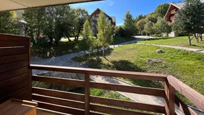 A balcony with a view of a green park, a pathway, and buildings in the background. - Elegant apartment with parking - 6 guests (Valloire)