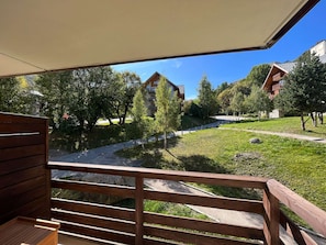 Ein Balkon mit Blick auf einen grünen Park, einen Weg und Gebäude im Hintergrund.