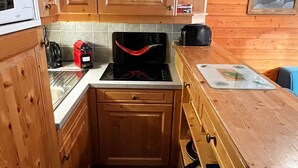 Eine kleine Küche mit Holzausstattung, einem Herd und einer Arbeitsplatte mit Schneidebrett.