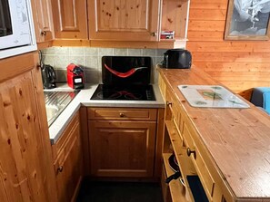 A compact kitchen with wooden cabinets, a stove, and a countertop with a cutting board. - Duplex apartment, parking - 6 guests (Valloire)