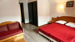 Ein Zimmer mit einem Bett, einer hölzernen Bank, einem roten Sofa und einer Tür.