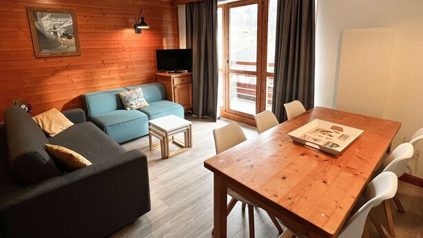 Ein gemütliches Wohnzimmer mit einer Couch, einem Couchtisch und einem Holzessttisch mit Stühlen.