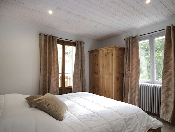 A bedroom with a bed, wooden wardrobe, and a window with curtains. - Central apartment, pets welcome - 6 guests (Valloire)