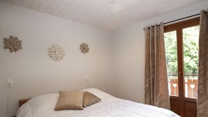 A bedroom with a wooden bed, white bedding, and three wall-mounted flower decorations. - Central apartment, pets welcome - 6 guests (Valloire)