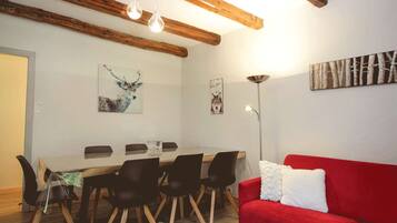 Un coin repas avec une table en bois, des chaises noires et un canapé rouge.