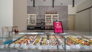 Una vetrina di pasticceria con diversi dolci e pasticcini, un cartello con il menu e un cartello con il premio Playnse's Choice.