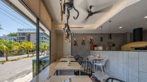 Un ristorante moderno con vista sulla strada, caratterizzato da tavoli e sedie in legno e una ventola a soffitto.