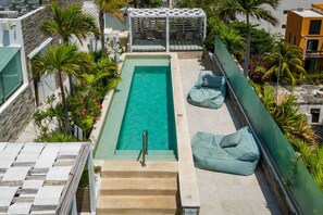 A rooftop pool with a clear view of the sky, surrounded by palm trees and a covered seating area. - Prime Location 1BR | Pool + Walk to the Beach (Playa del Carmen)