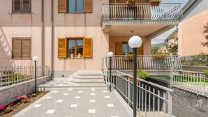 A building with a balcony, steps leading to the entrance, and a paved area with plants. - Villa 'Il Vulcano di Milo' (Milo)
