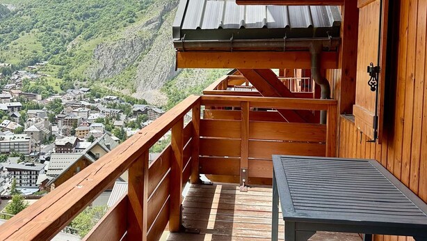 Un balcón de madera con vistas a un pueblo y montañas.