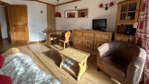 Un soggiorno con tavolo da pranzo in legno, sedie, divano, televisore e mobile.