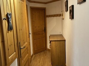 Eine Holztür, ein kleines Schränkchen und eine Wand mit gerahmten Bildern.