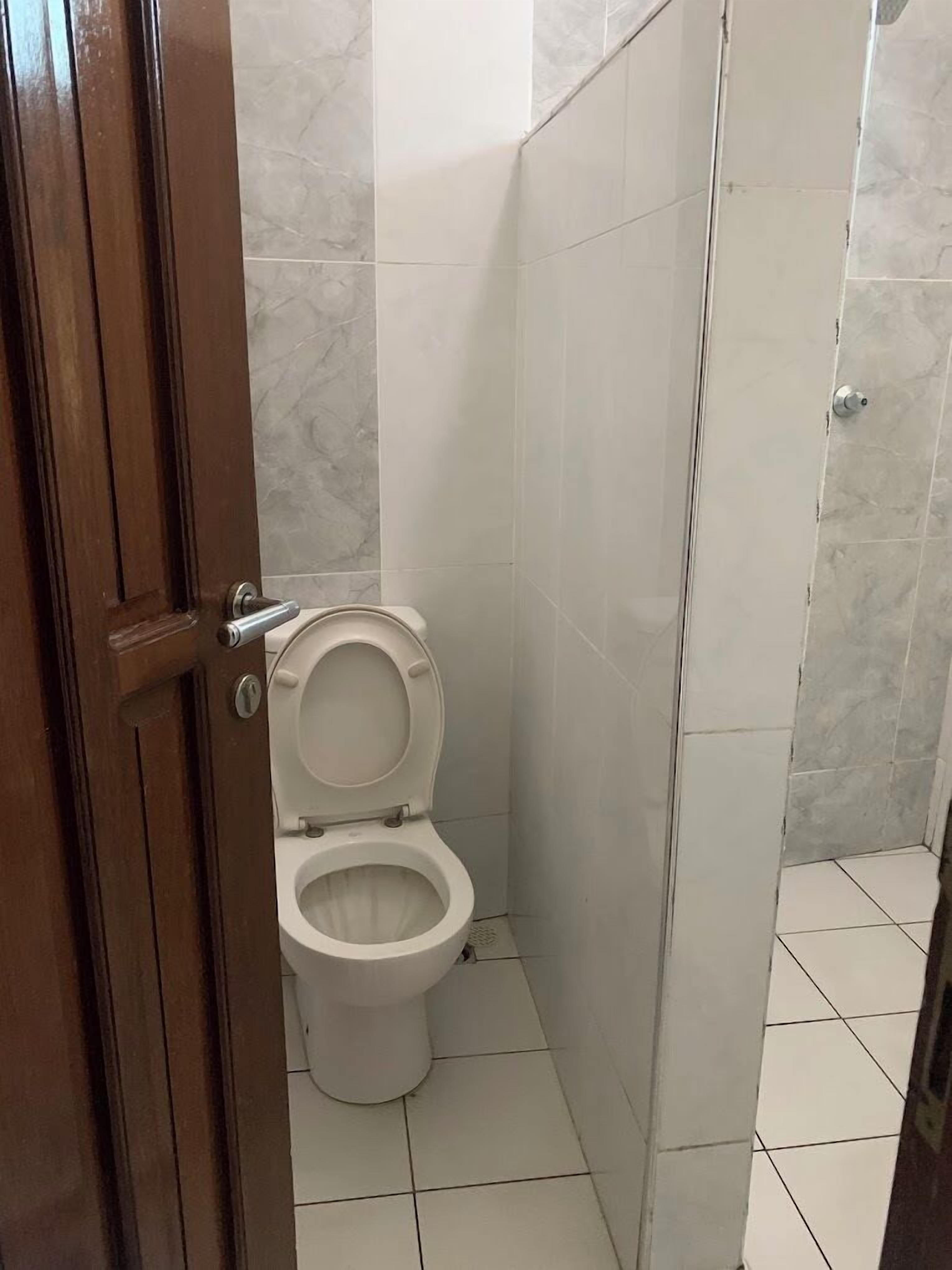Une salle de bain avec des toilettes, un espace douche et une porte.