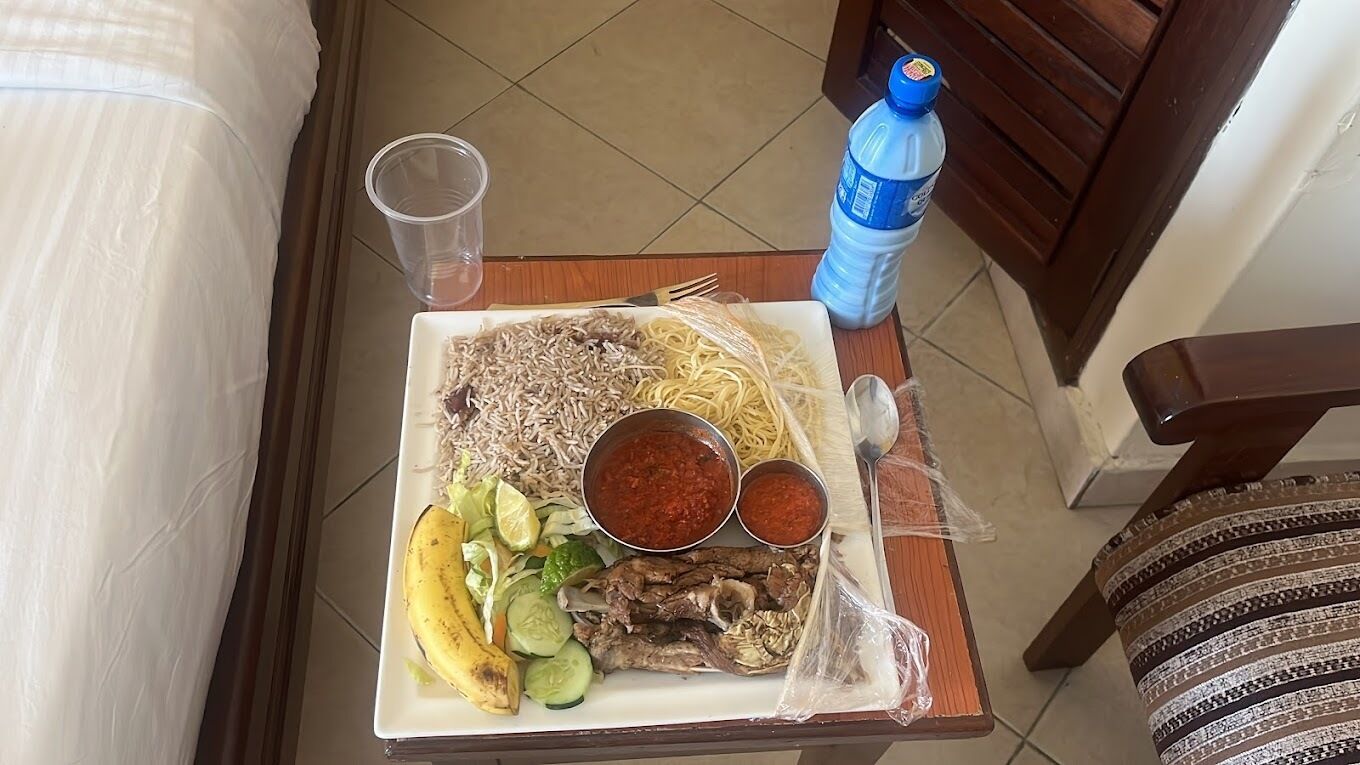 Una bandeja con alimentos como arroz, fideos, carne y verduras, un plátano y dos recipientes de salsa.