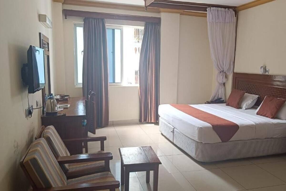 Une chambre d’hôtel avec un lit, une télévision, un bureau et une chaise.