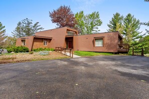 A modern two-story house with a paved driveway, a front porch, and a small deck.